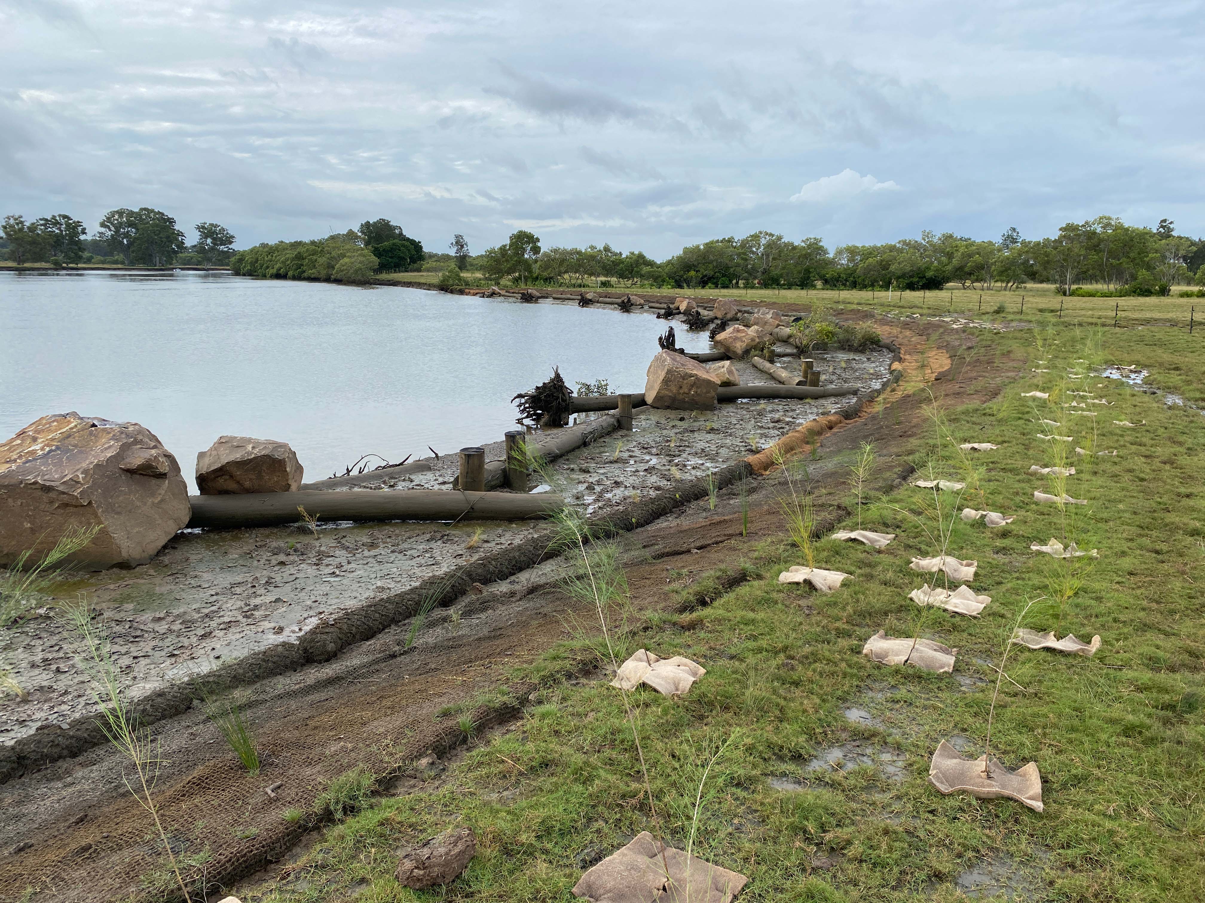 A large bend in a river, with rocks and logs placed along the bank to prevent washaway.