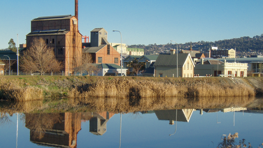 A wide river with houses and a view of the city on the opposite bank.