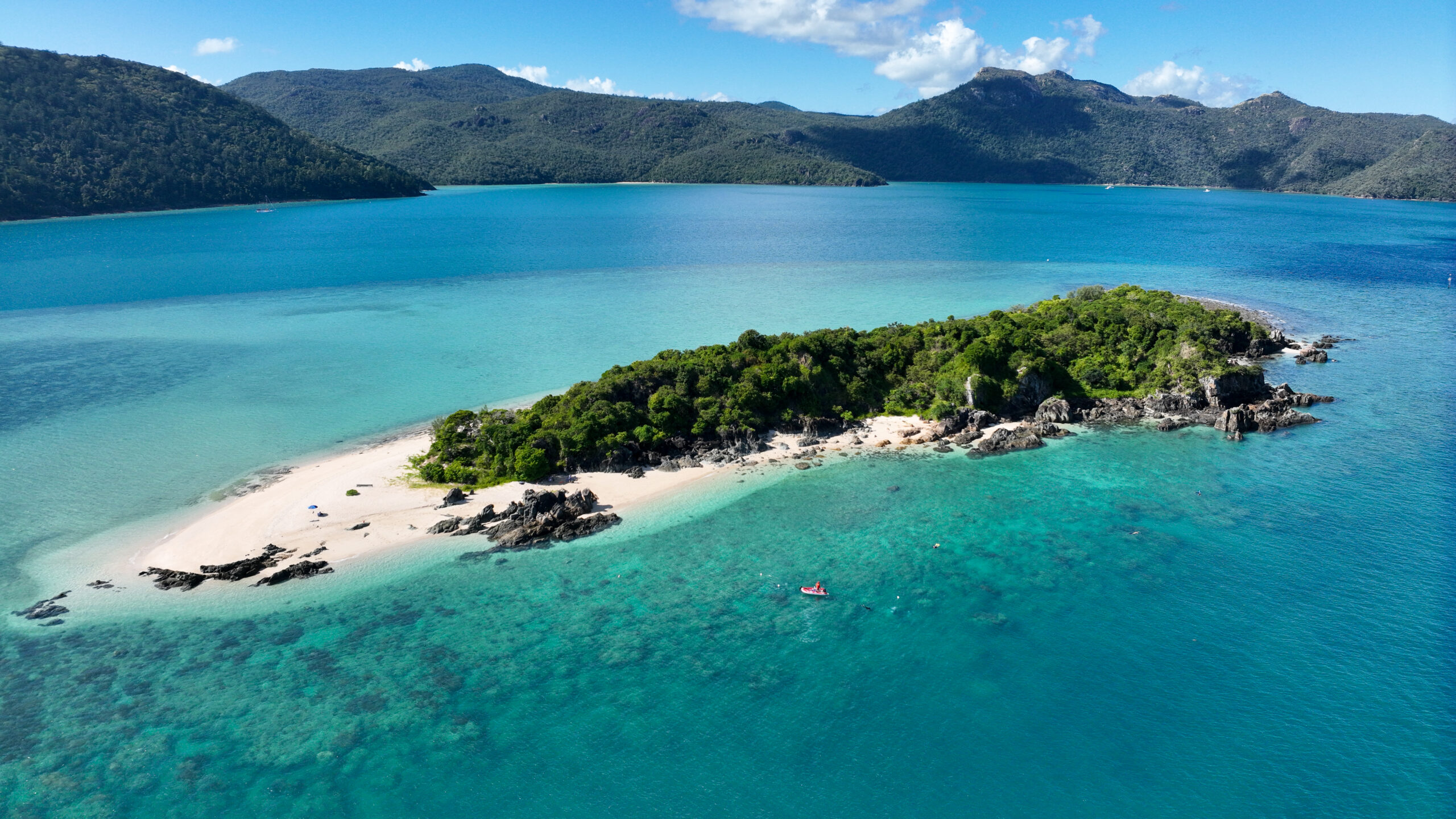An aerial photo of an island, with the mainland in the distance.