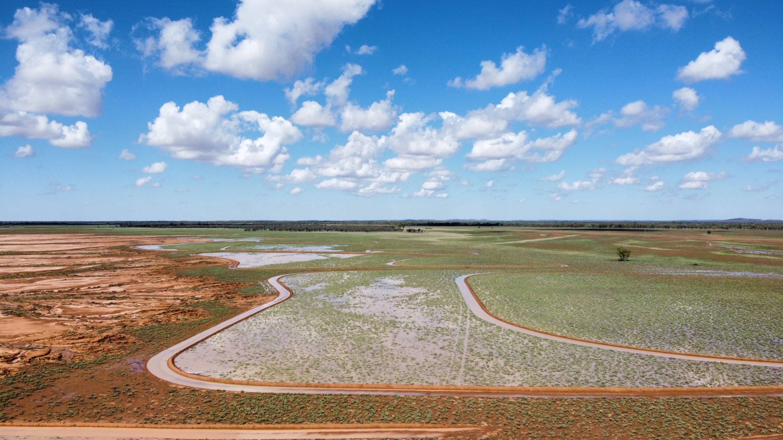 An aerial photo of a large expanse of cleared land, with water in channels cutting through it.