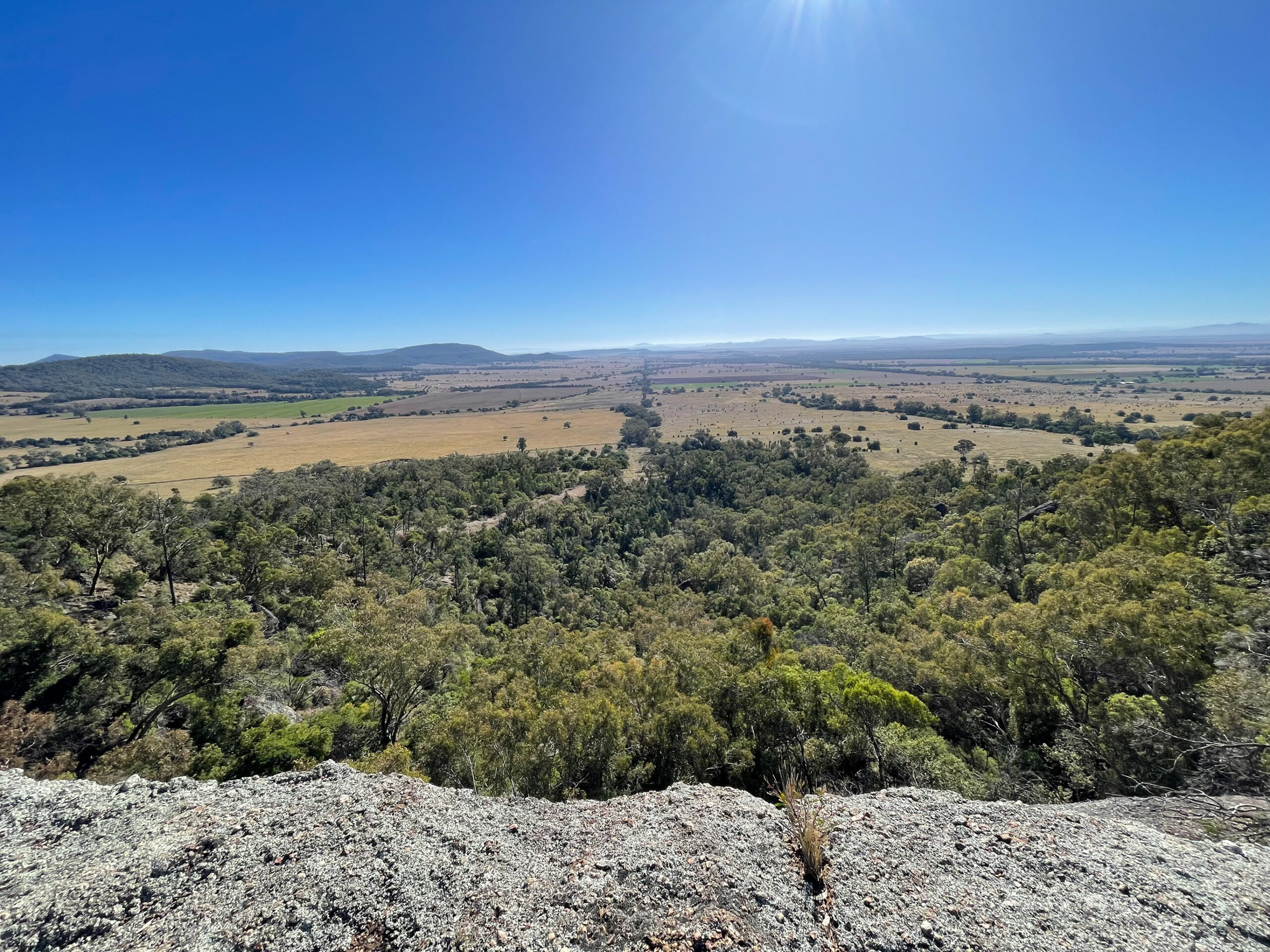 A photo taken from the top of a hill, looking out over trees and open fields.