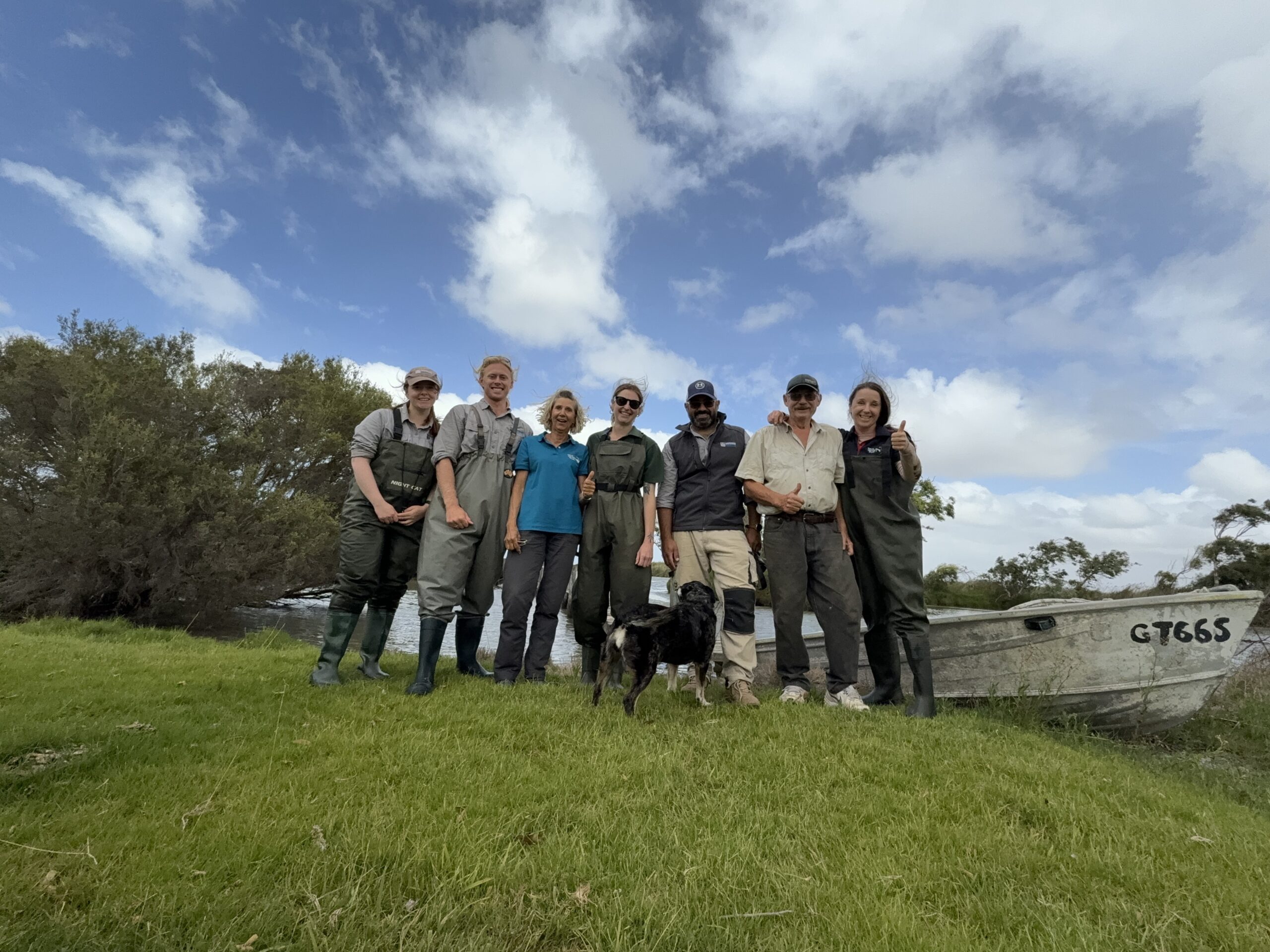 A group photo of people in front of a small boat.