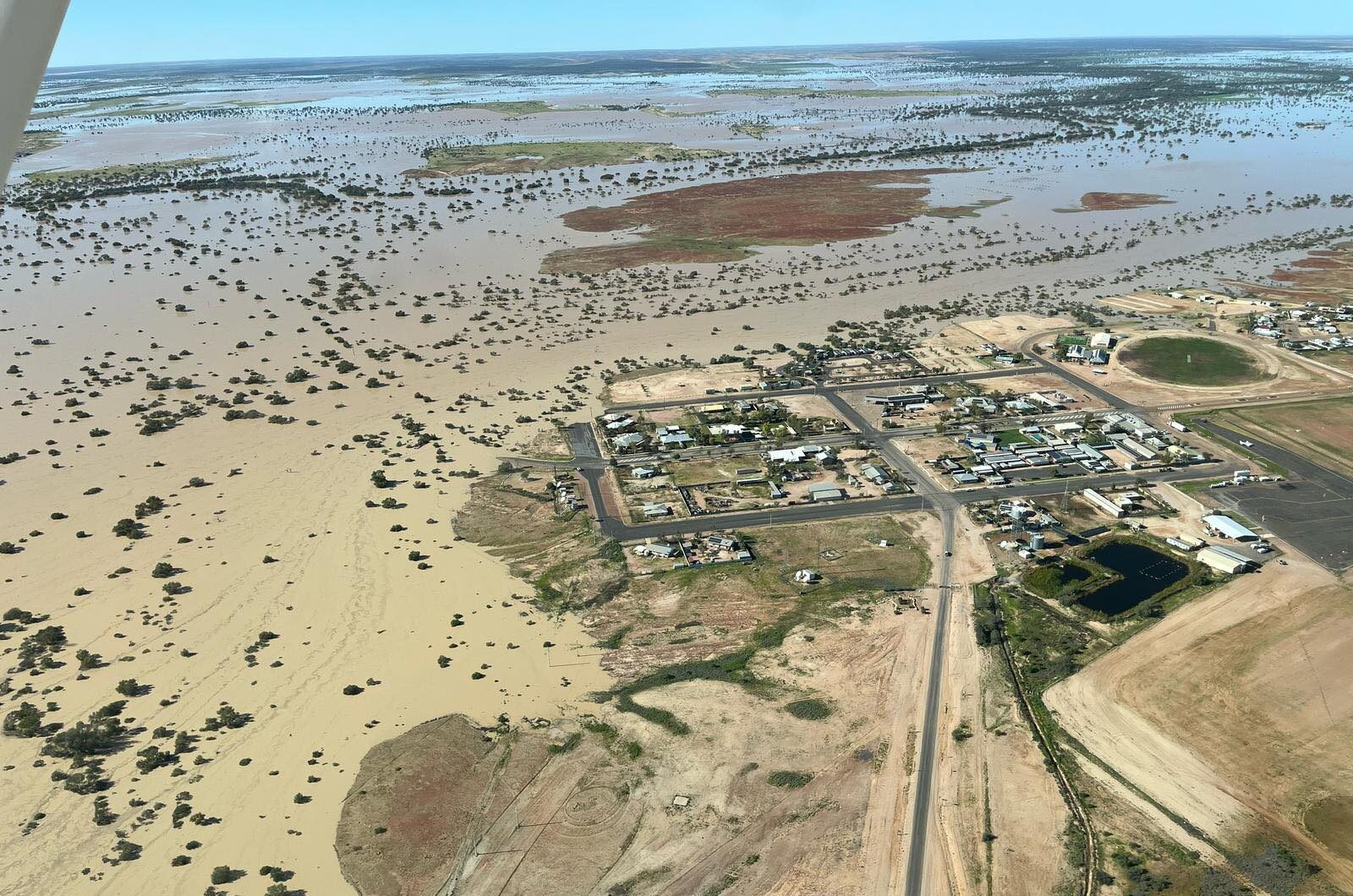 Aerial view of a town in the edge of a vast flooded plain.