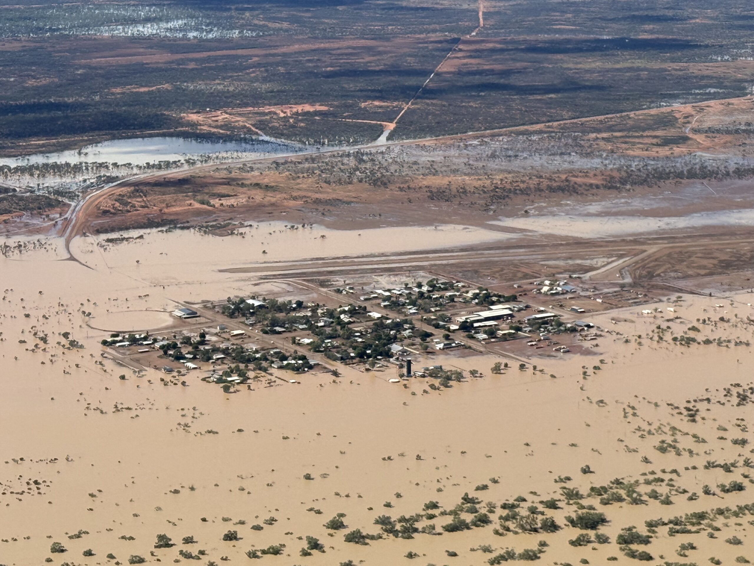 Aerial view of a half-flooded town on the edge of a flooded plain.