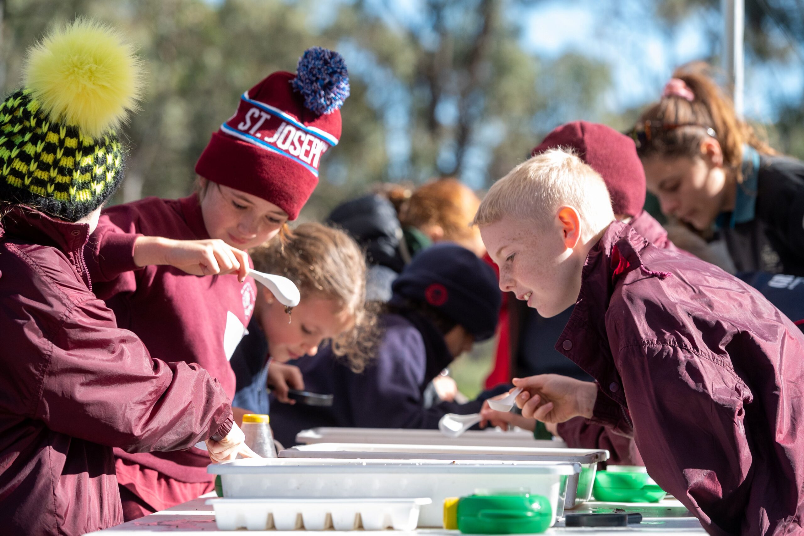 A group of children gathered around small plastic tubs examining the contents.