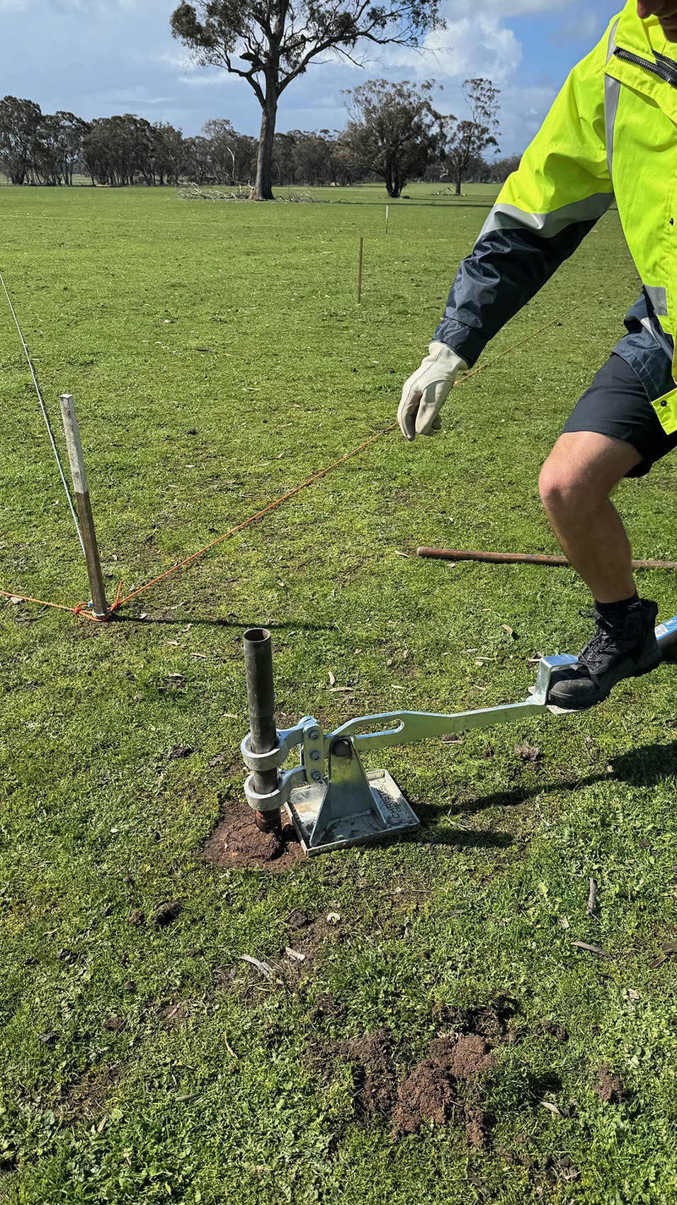A person is using a metal device, that is inspecting the soil, the person has their foot on the device.
