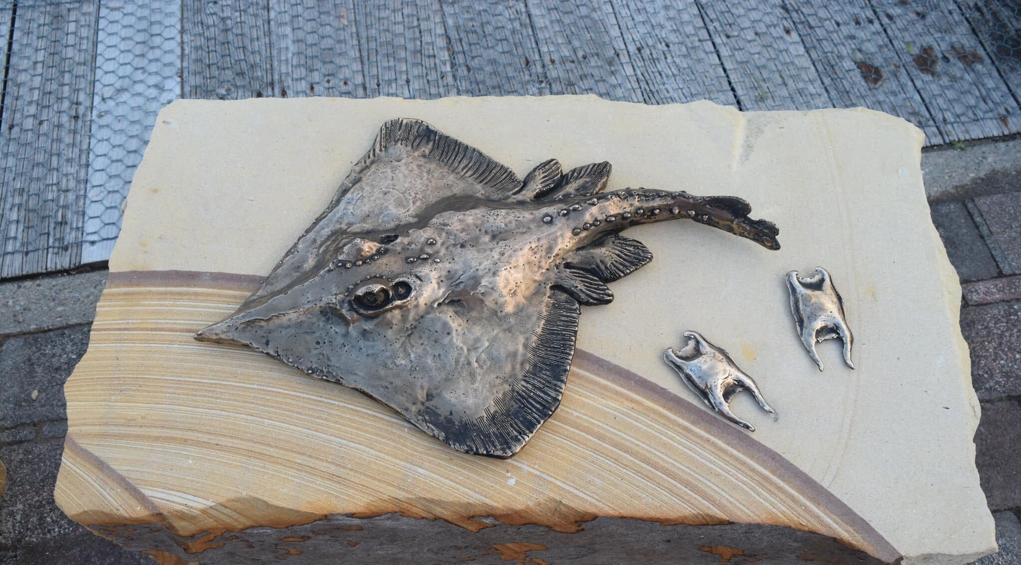 A steel sculpture of a skate on top of a sandstone block.